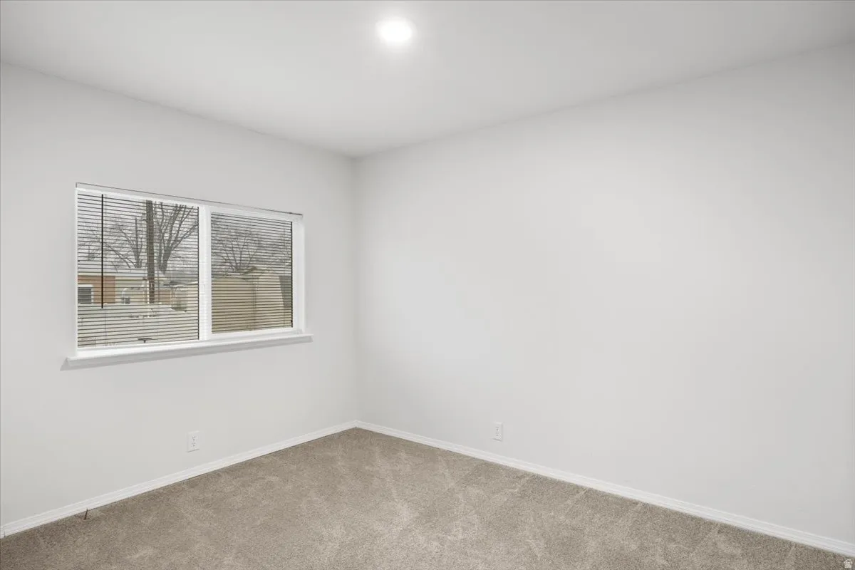 Unfurnished room featuring light colored carpet and baseboards