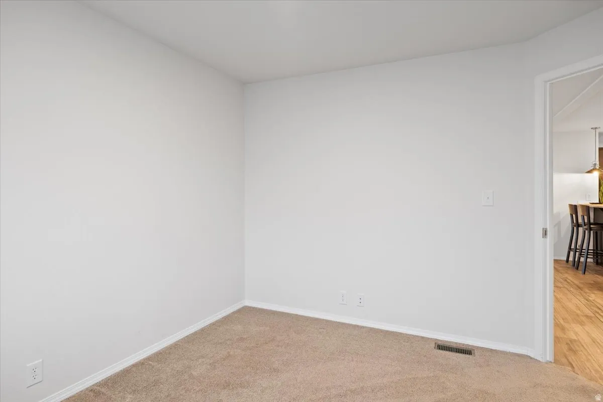 Empty room featuring light colored carpet and baseboards