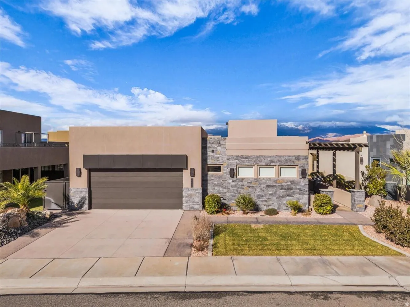 View of front of property featuring concrete driveway, stucco siding, a garage, and stone siding