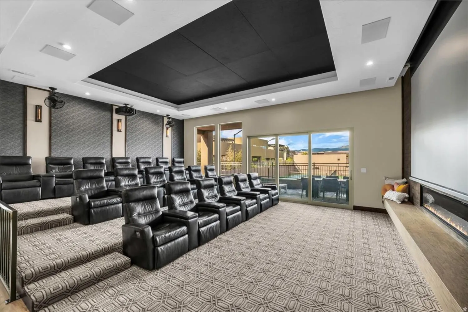 Cinema with light carpet, an accent wall, and a tray ceiling