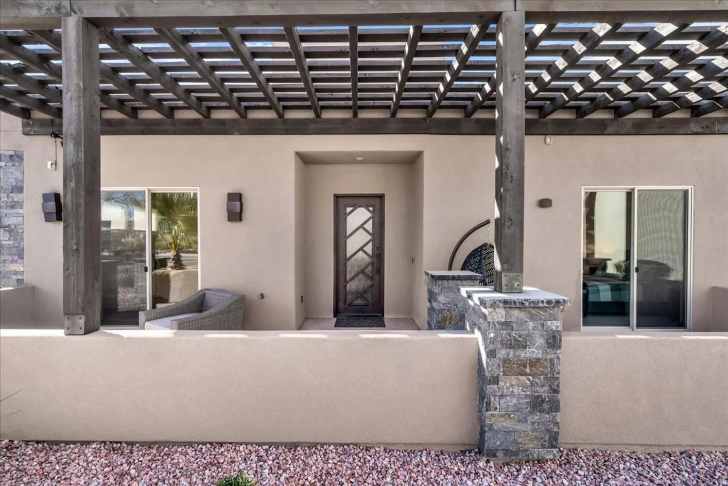 View of exterior entry with a patio, a pergola, and stucco siding