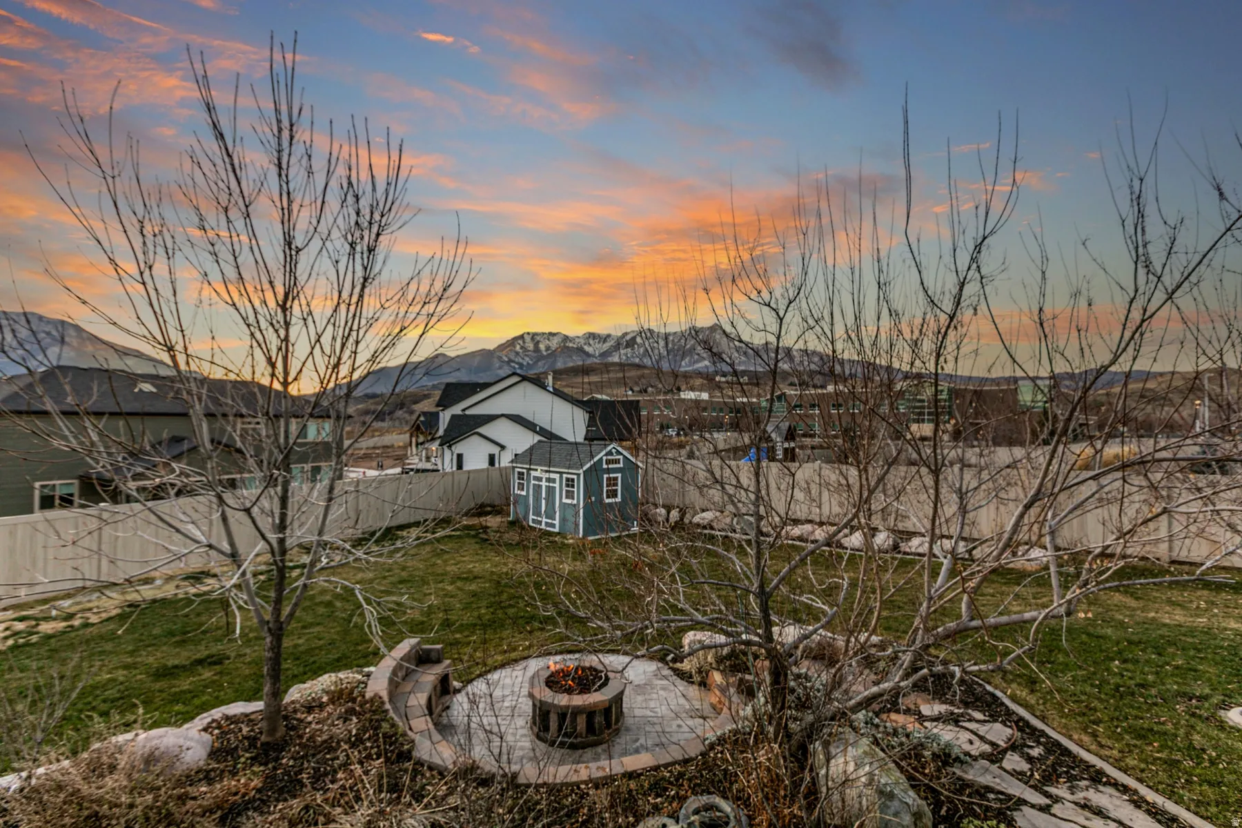 Back of house with a fenced backyard, a storage unit, an outdoor fire pit, and a mountain view