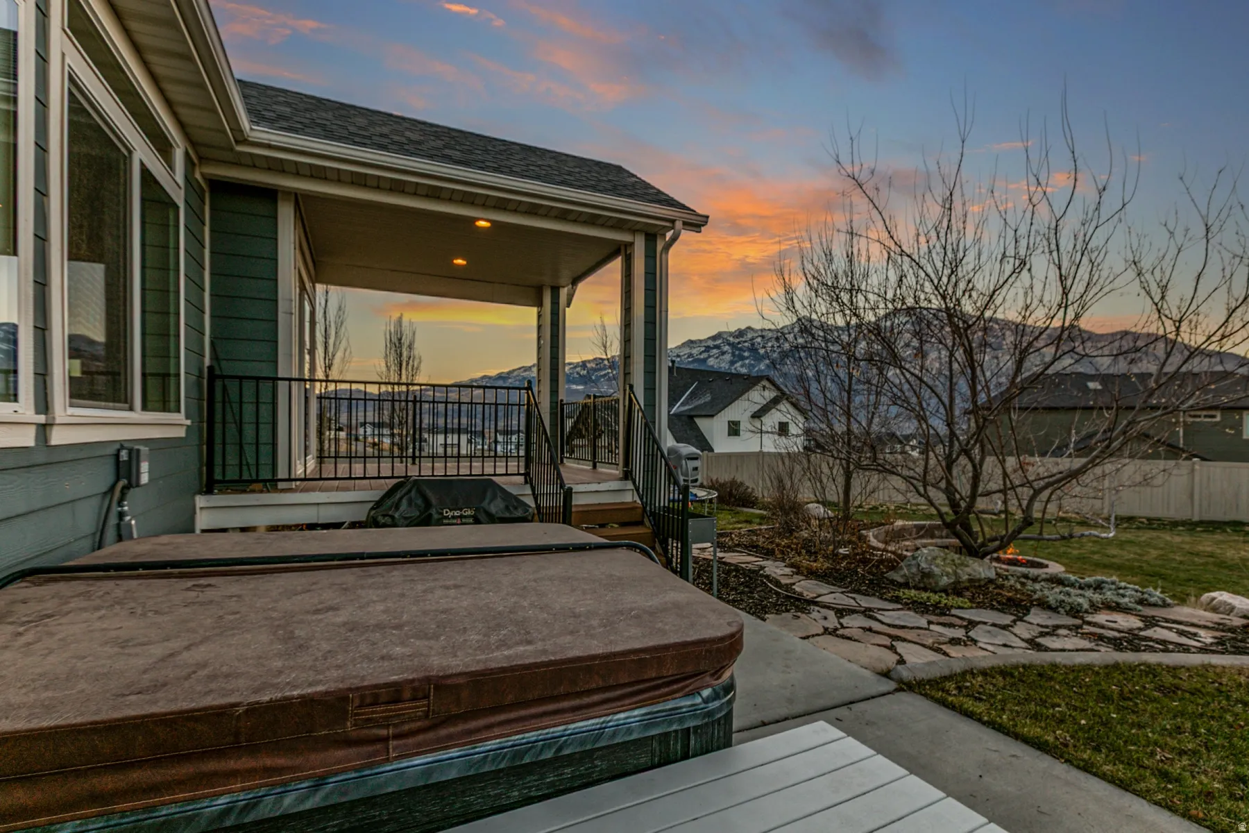 Deck at dusk featuring a hot tub and a patio area