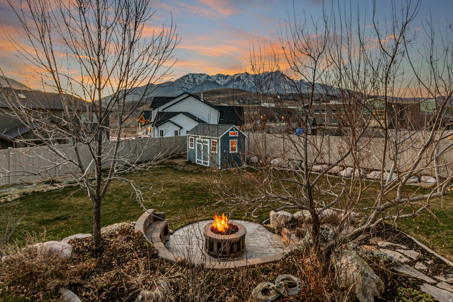 Fenced backyard featuring a mountain view, a shed, and a fire pit