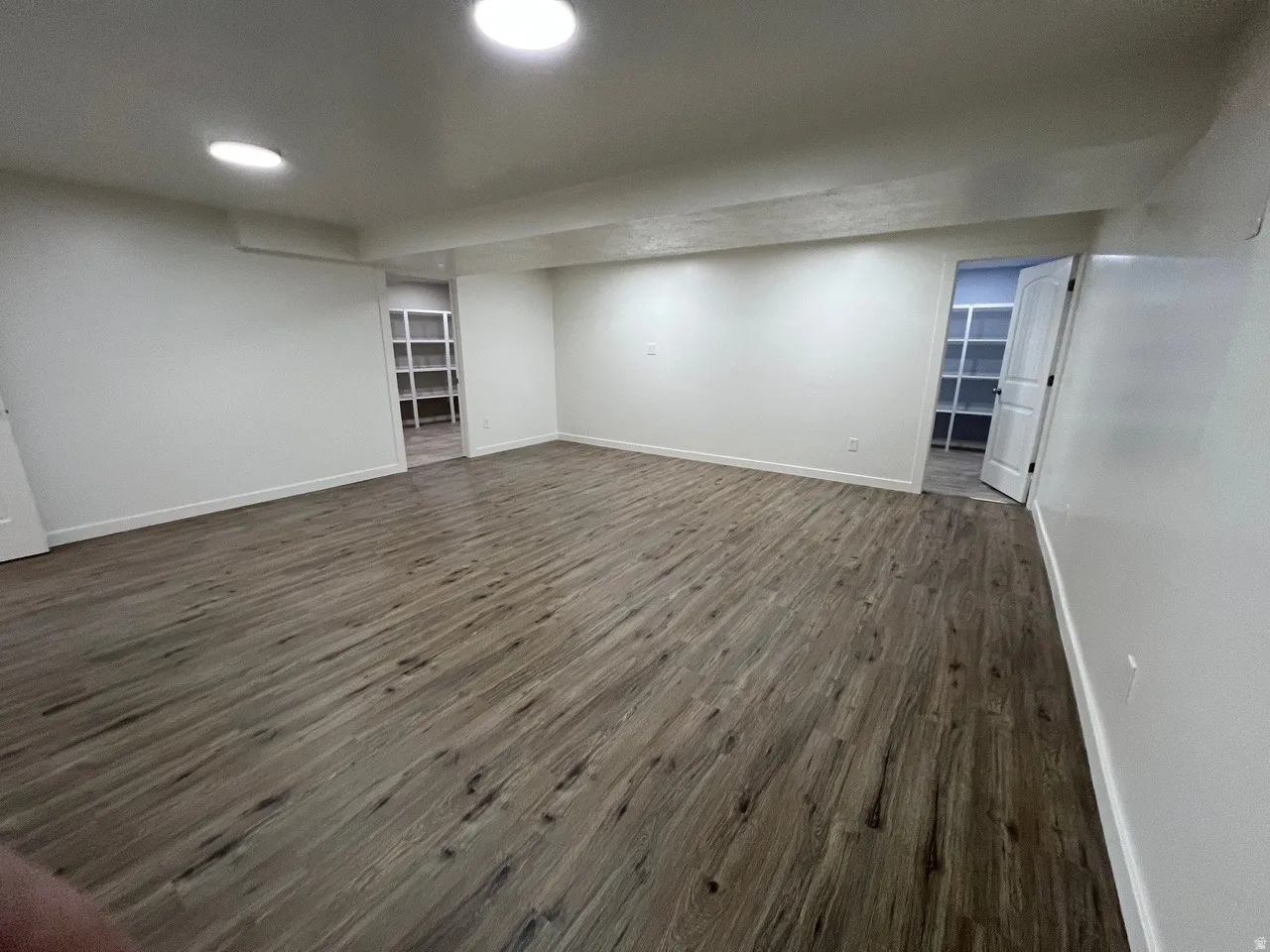 Finished below grade area with dark wood-type flooring and baseboards