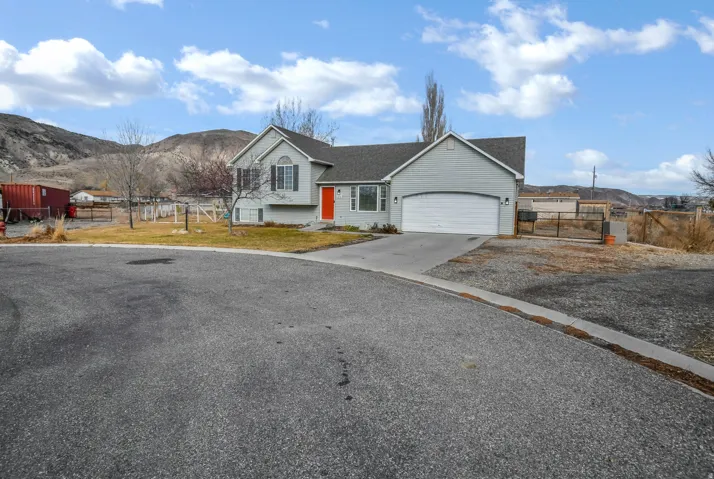 View of front of property featuring a mountain view, concrete driveway, a gate, and a garage.