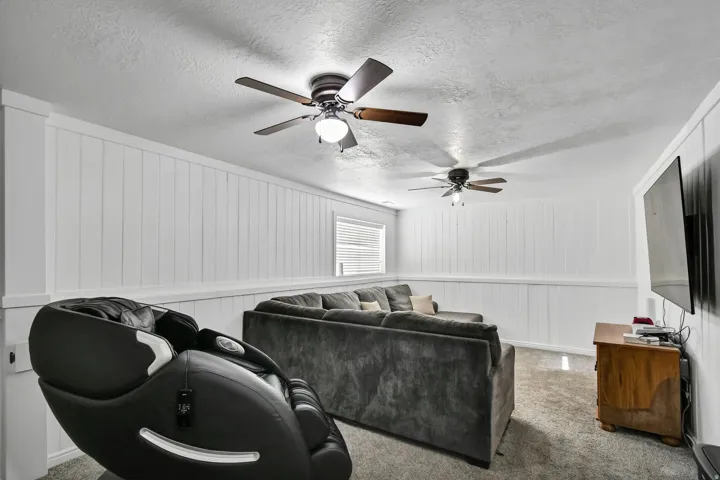 Living area featuring a textured ceiling, a ceiling fan, and carpet