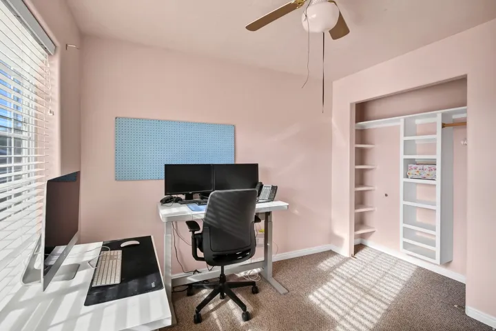 Carpeted office with ceiling fan and built in features