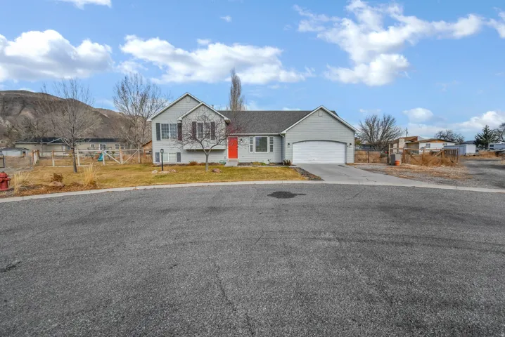View of front of property featuring concrete driveway, a gate, and a garage.