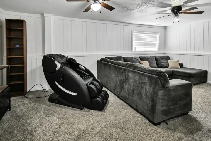 Carpeted living room featuring ceiling fan and a textured ceiling