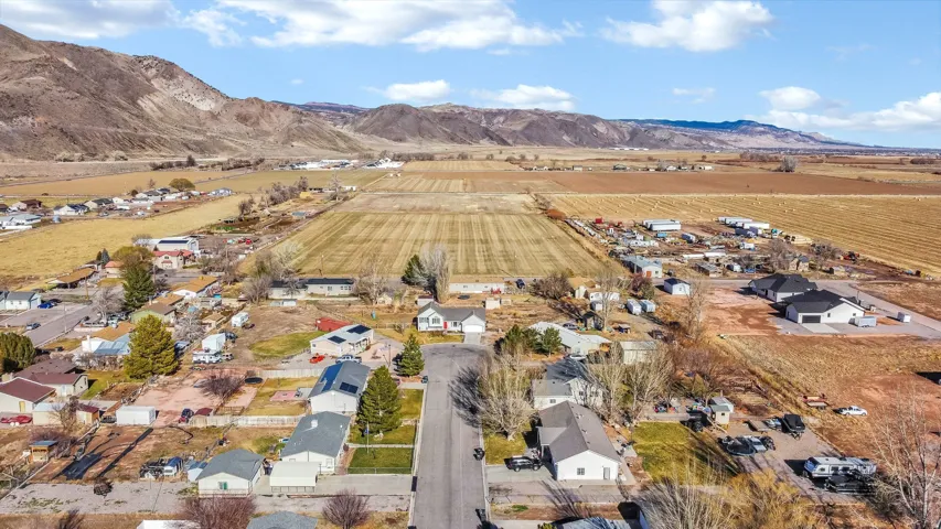 Aerial overview of property's location with a mountainous background, rural landscape, and rows of crops
