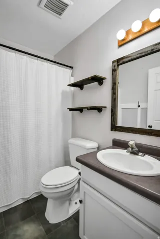 Bathroom featuring a shower with shower curtain, vanity, and dark tile patterned floors