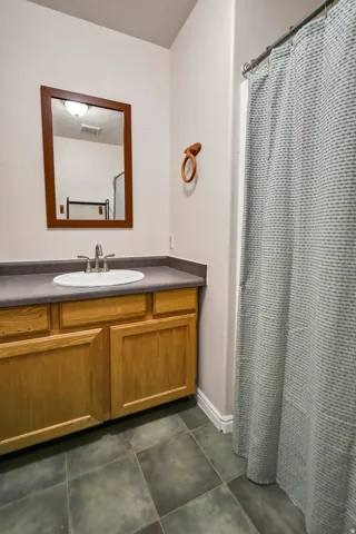 Full bath with vanity, curtained shower, and dark tile patterned floors