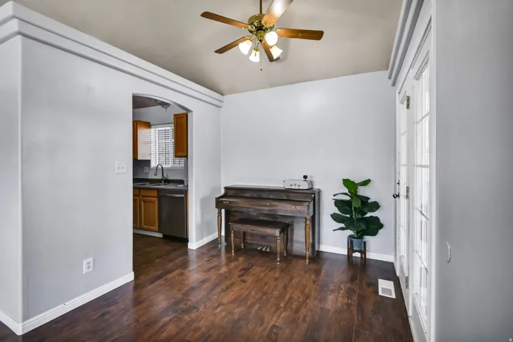 Living area featuring arched walkways, dark wood-style floors, and a ceiling fan