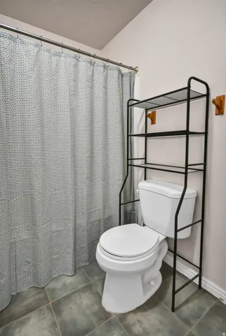 Bathroom featuring curtained shower and dark tile patterned flooring