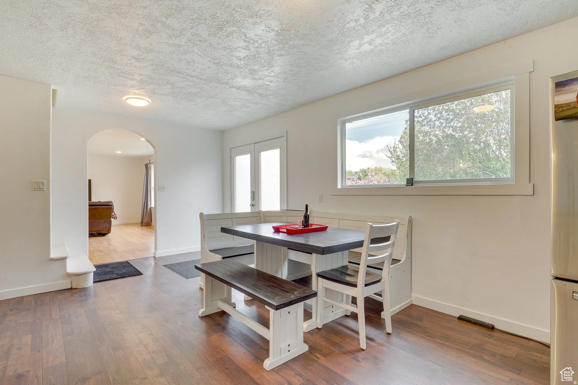 Dining area featuring arched walkways, a textured ceiling, wood finished floors, and french doors