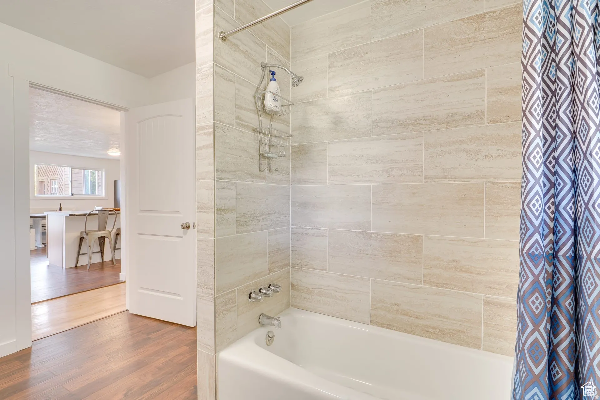 Full bath featuring shower / tub combo with curtain and wood finished floors