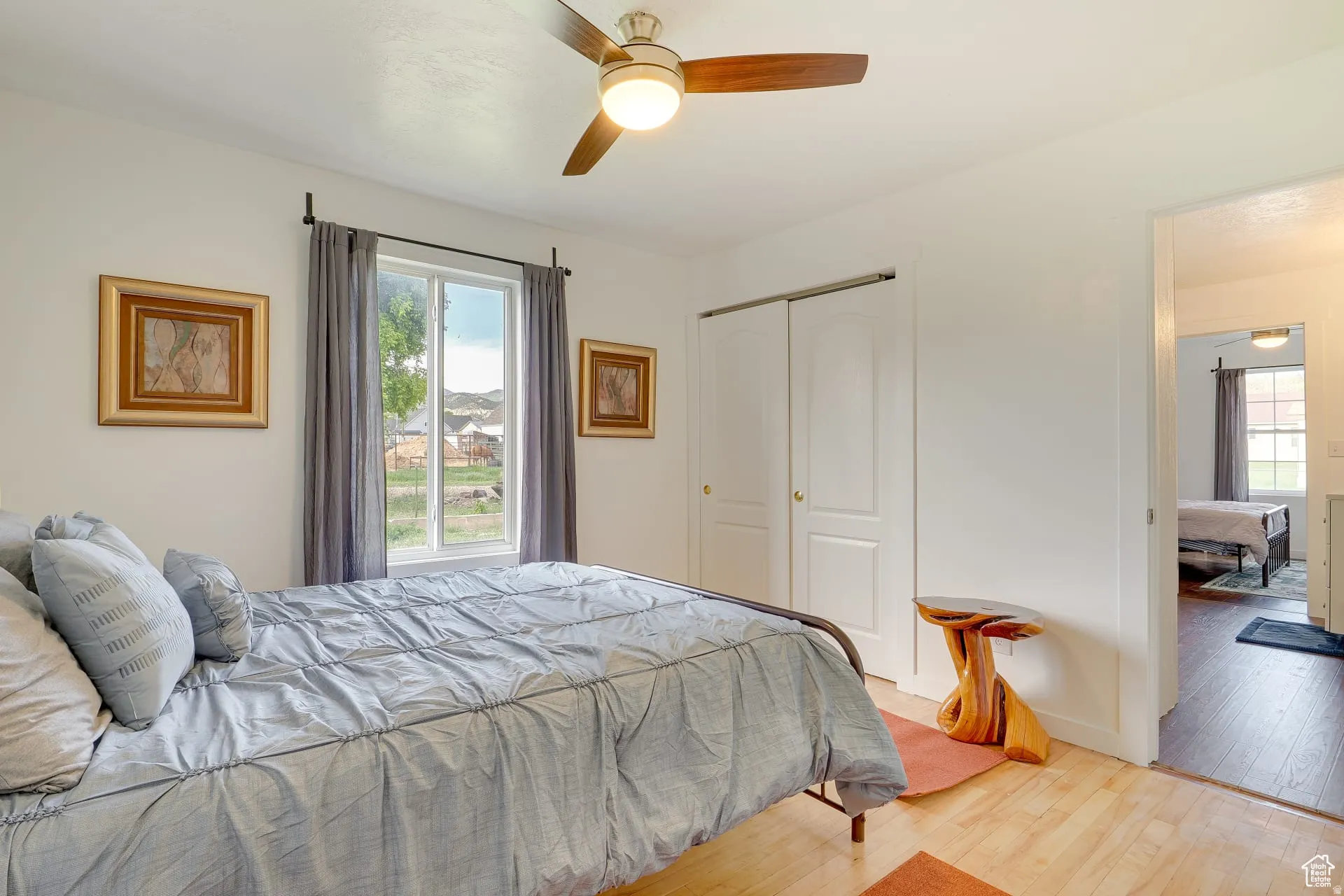 Bedroom featuring light wood finished floors, multiple windows, ceiling fan, and a closet