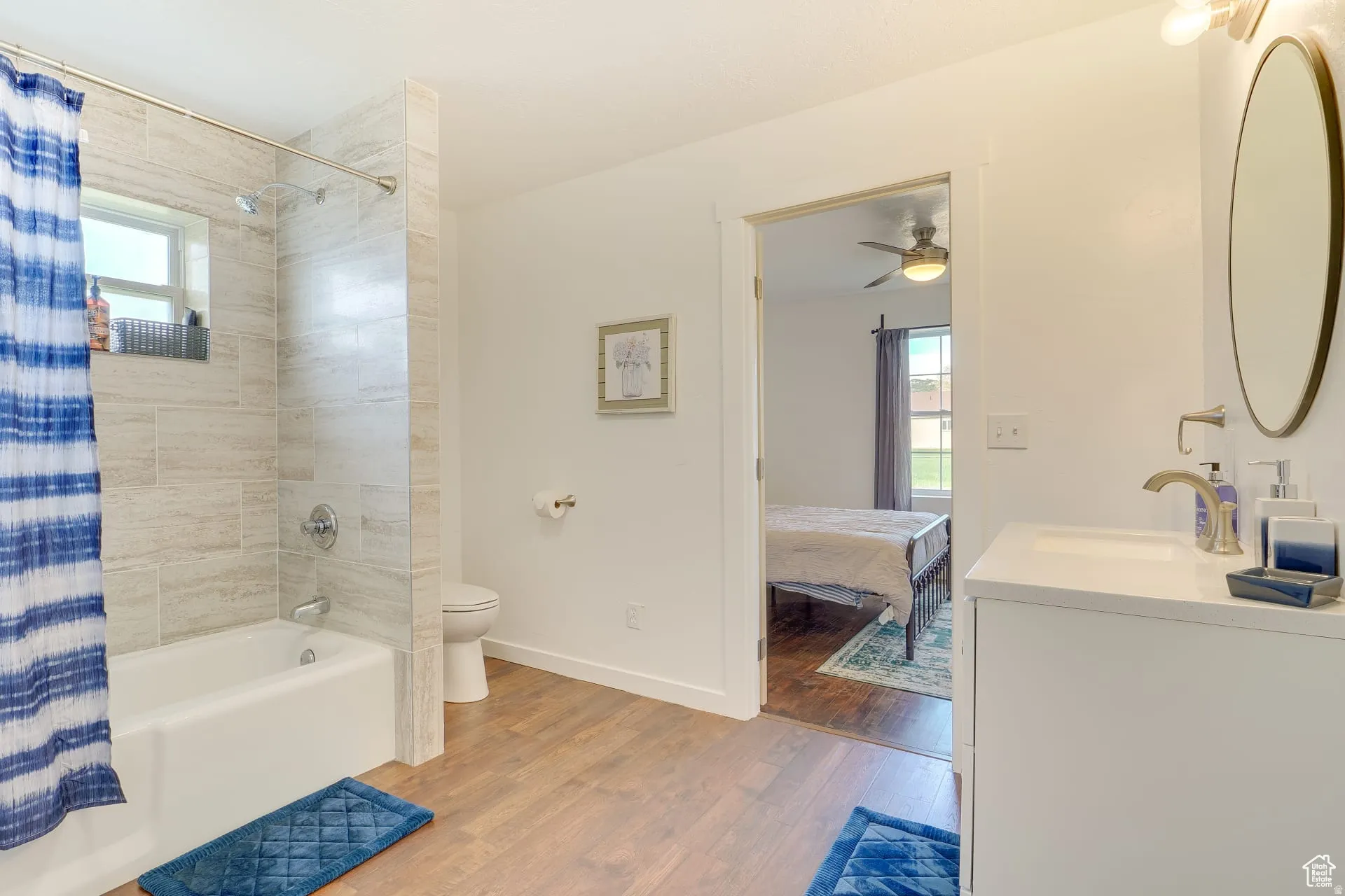Ensuite bathroom featuring shower / tub combo, vanity, and wood finished floors