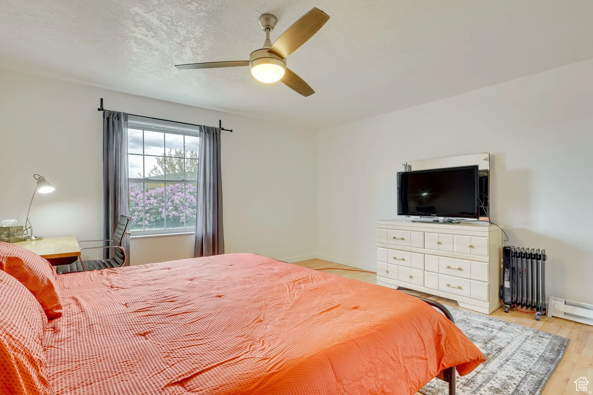 Bedroom featuring radiator, ceiling fan, light wood-style flooring, and a textured ceiling