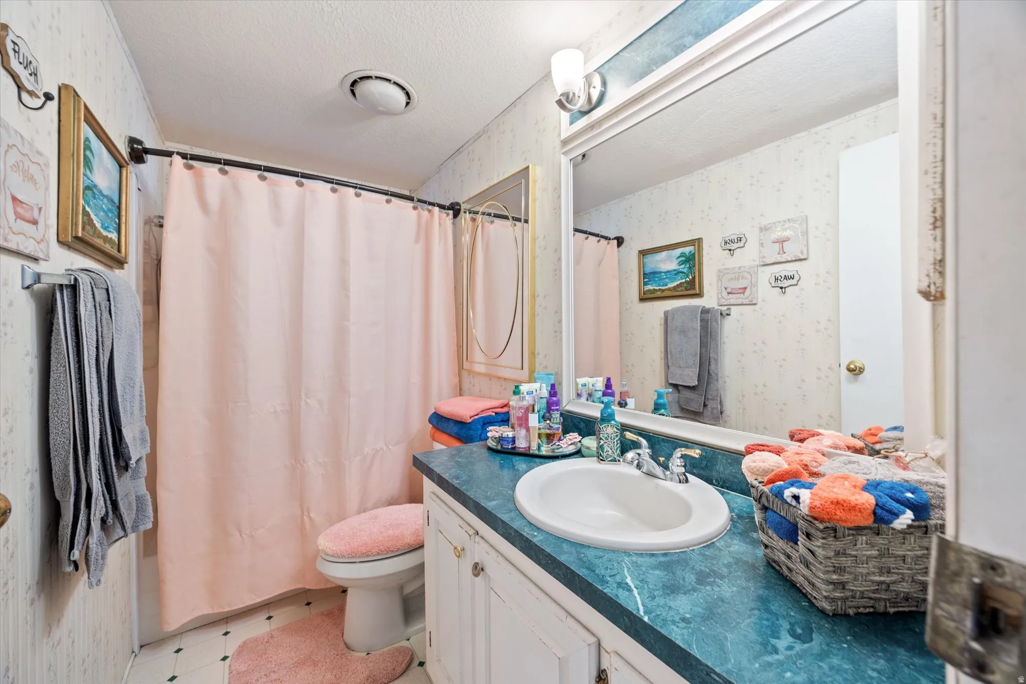 Bathroom featuring wallpapered walls, a shower with shower curtain, a textured ceiling, vanity, and light flooring