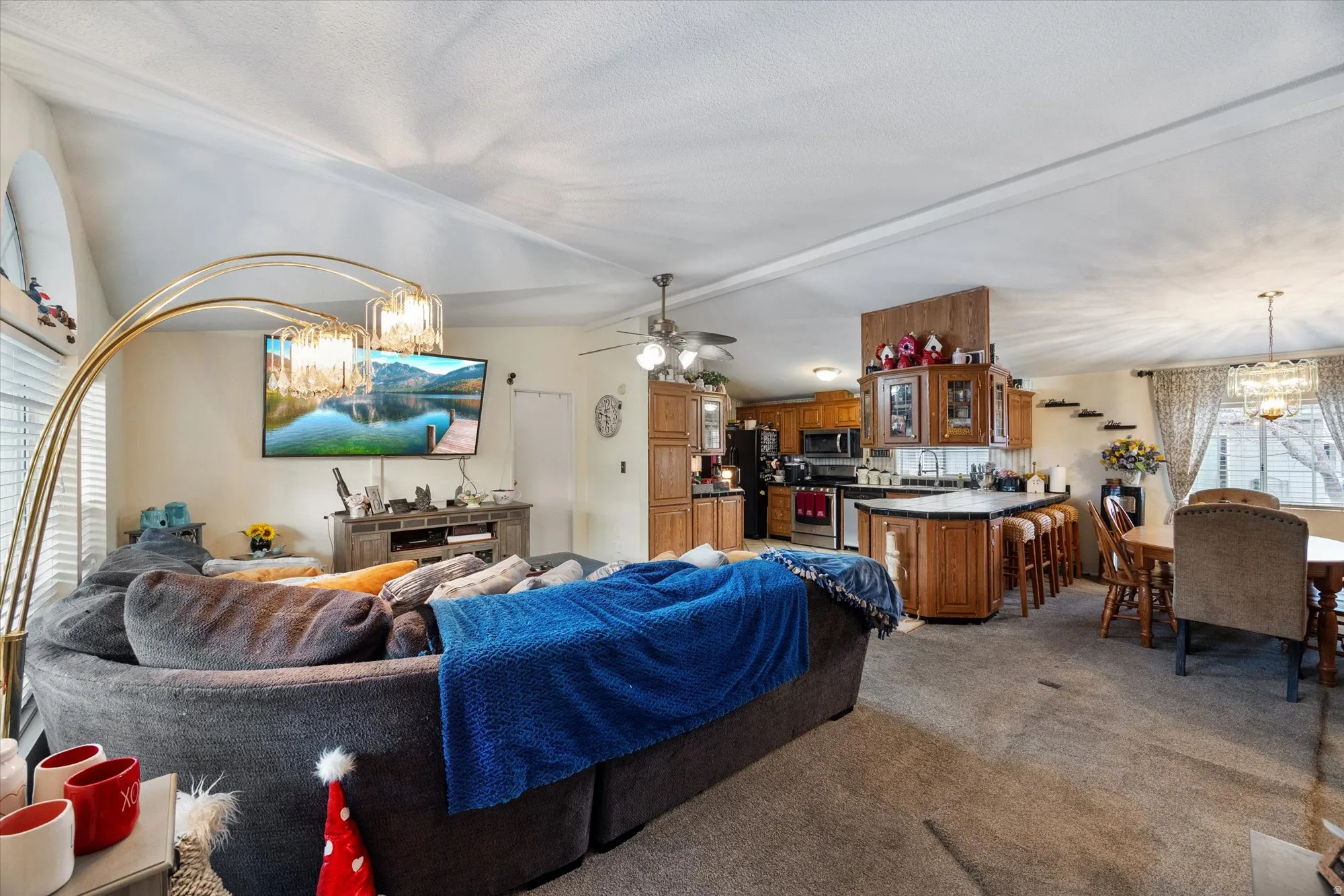 Living room featuring a chandelier, vaulted ceiling, ceiling fan, and light colored carpet