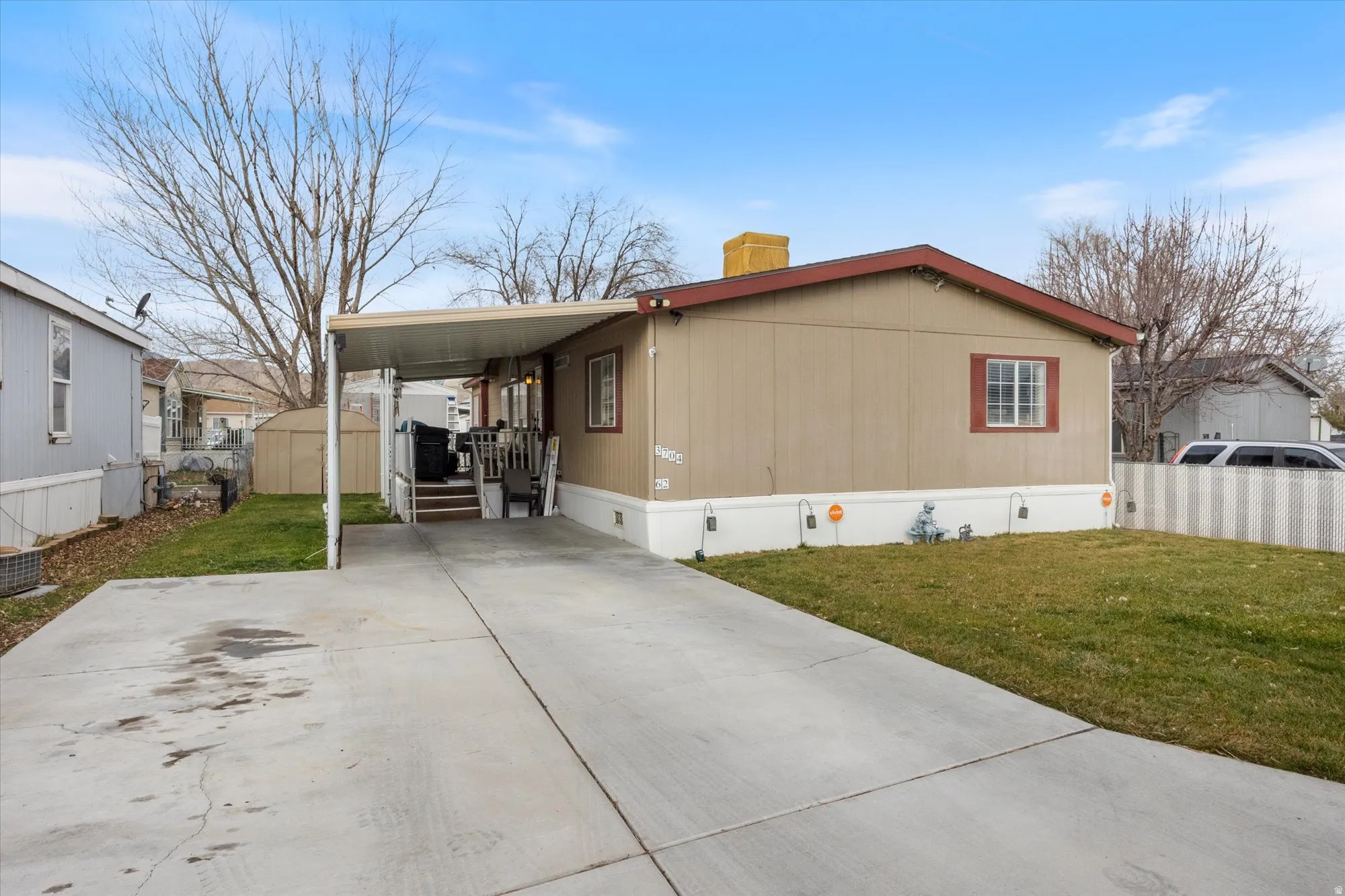 View of side of property with crawl space, a storage unit, a wooden deck, a chimney, and driveway