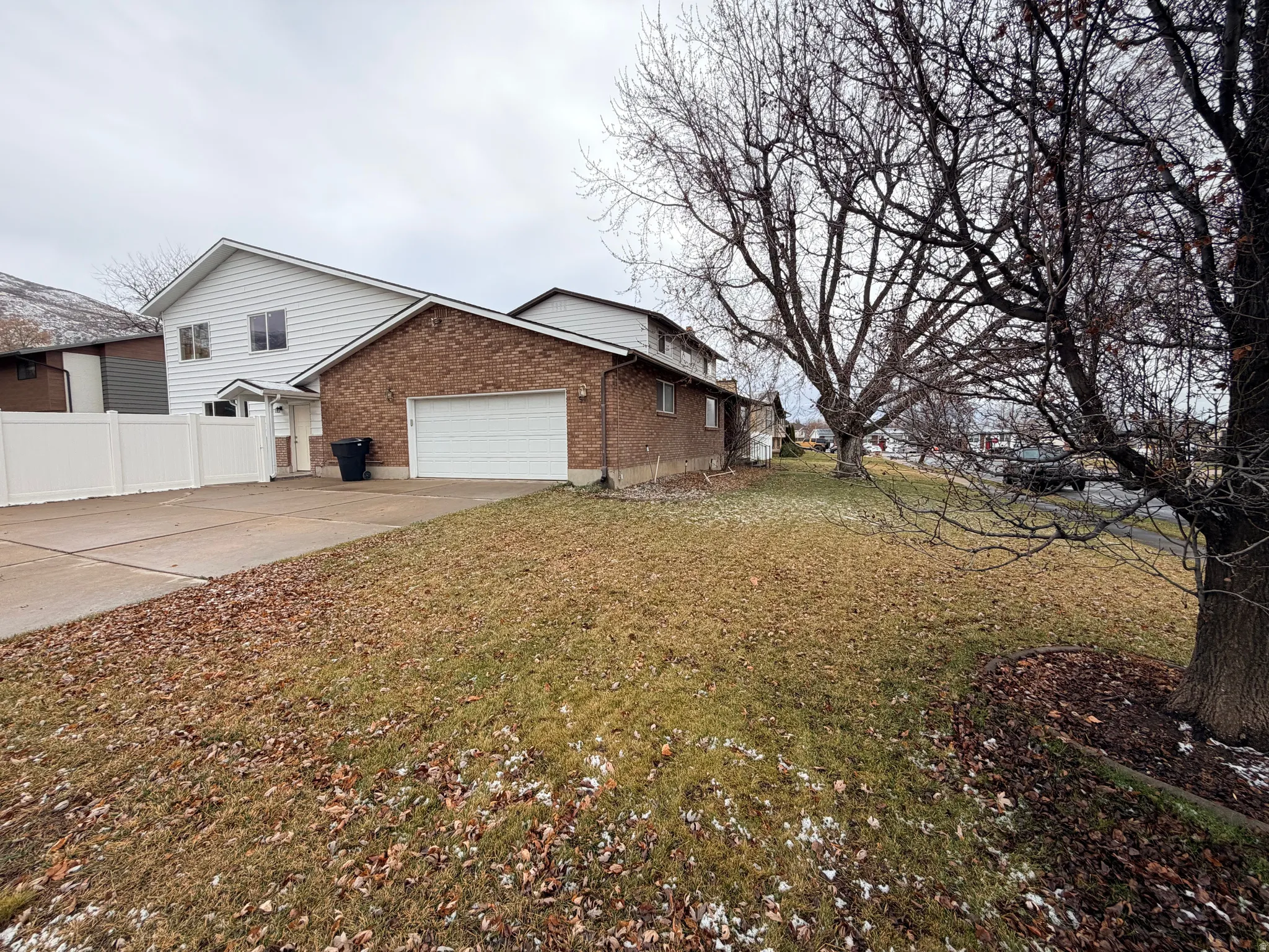 View of side of property with brick siding, concrete driveway, and an attached garage