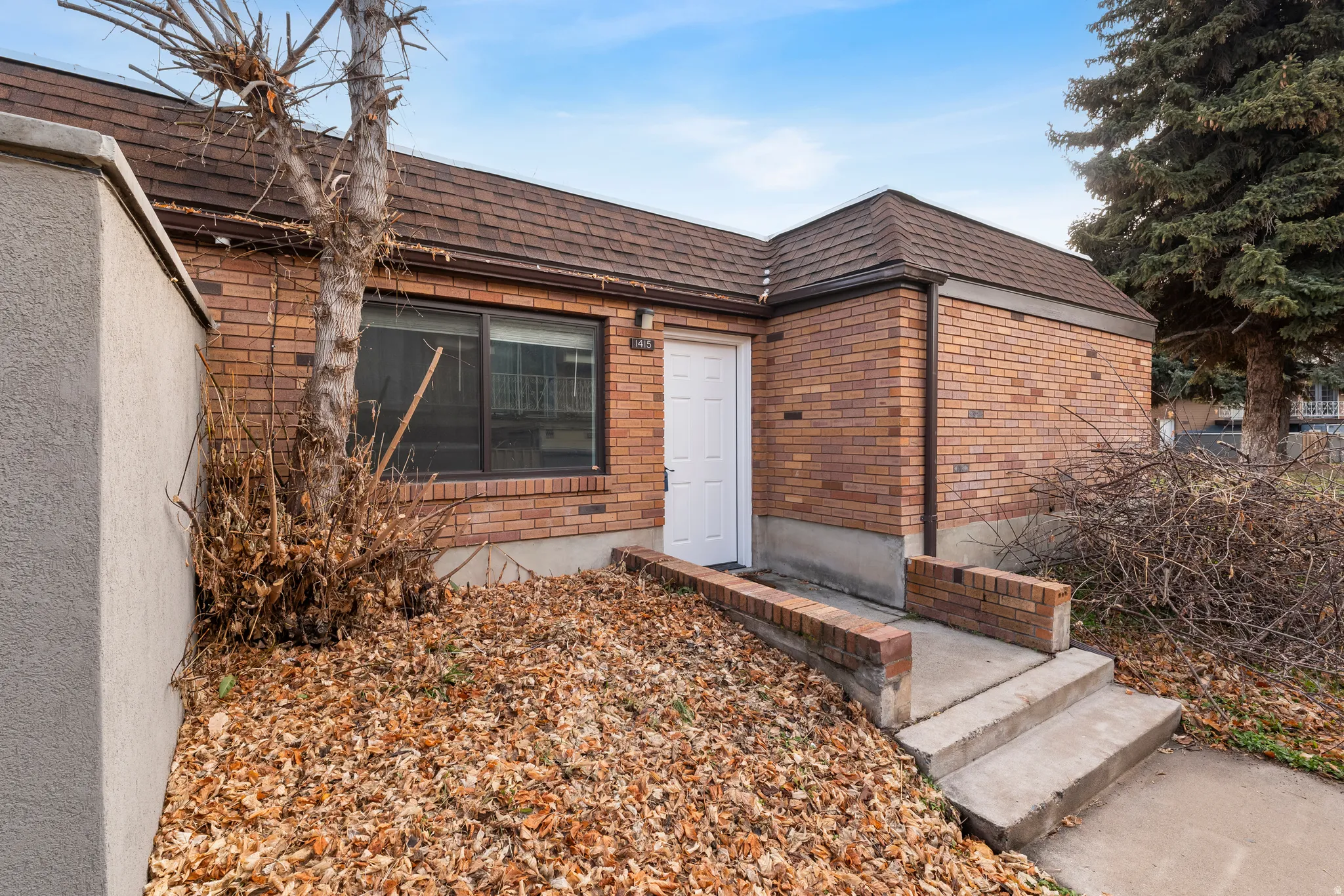 View of exterior entry featuring brick siding, a shingled roof, and mansard roof