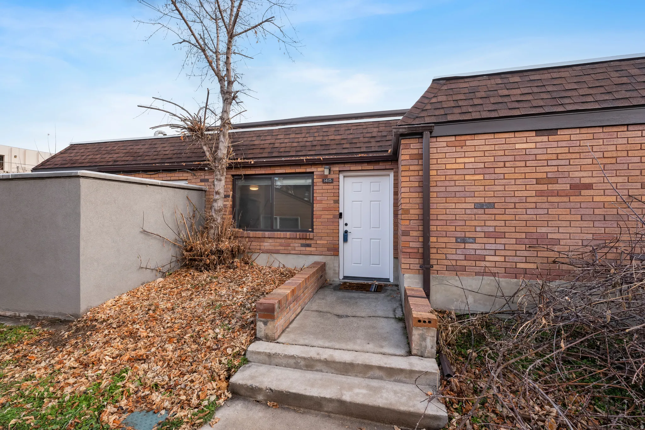 Entrance to property with brick siding and a shingled roof