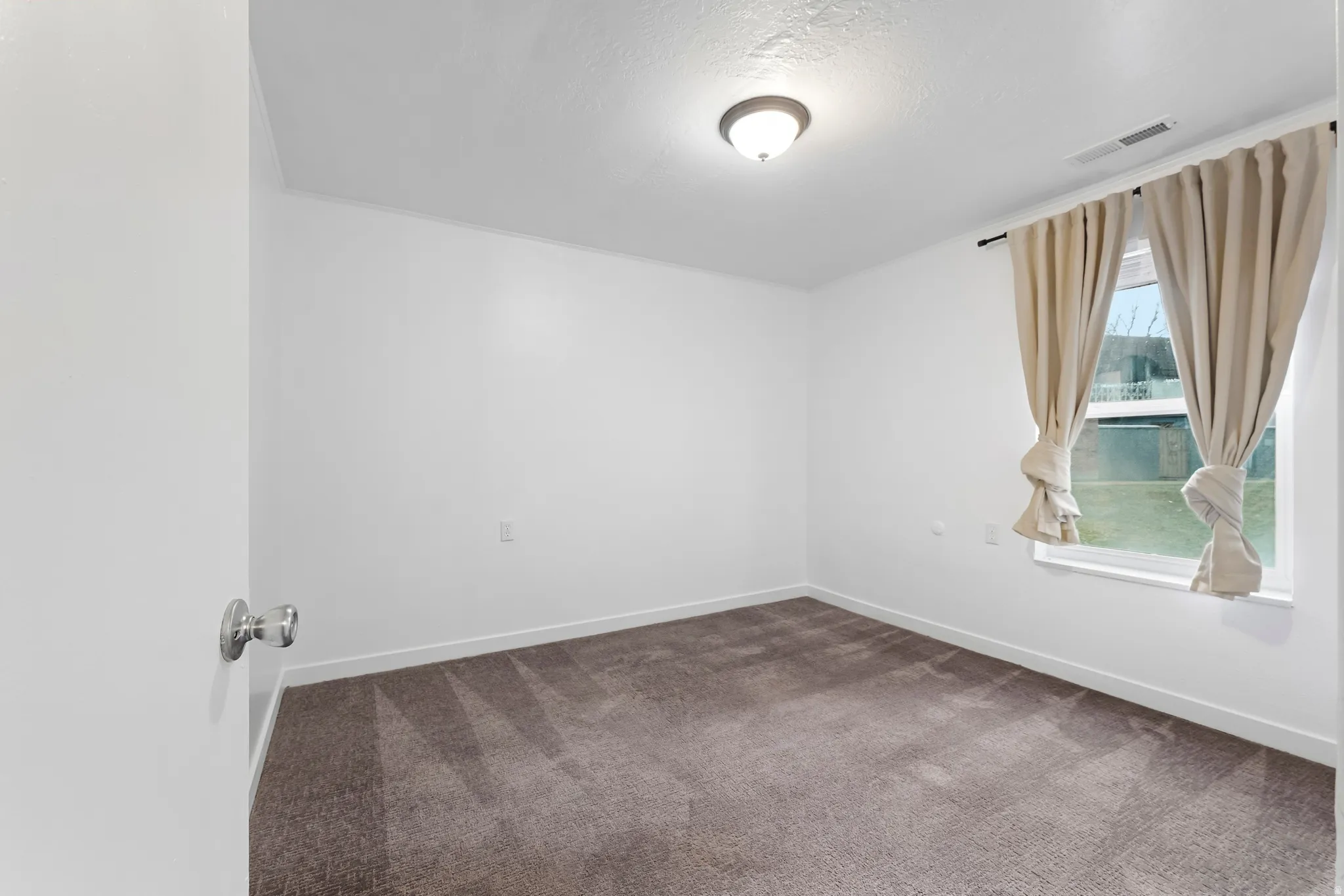 Empty room featuring carpet flooring and a textured ceiling