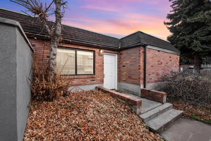 Property entrance with brick siding, mansard roof, and a shingled roof