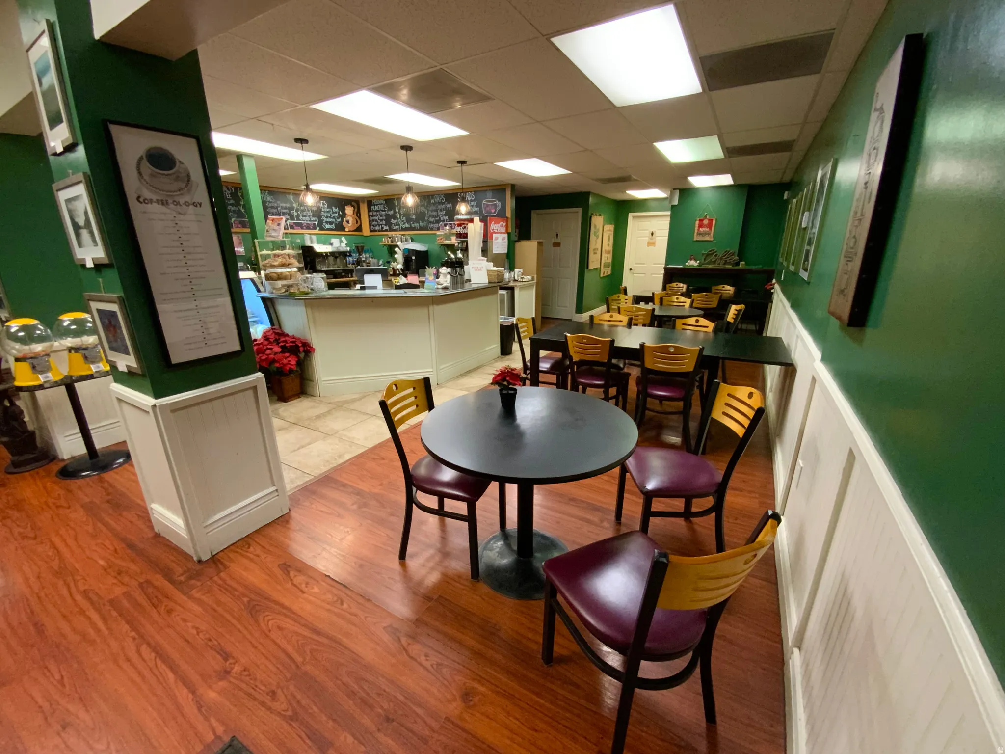 Dining room featuring a drop ceiling, wood finished floors, wainscoting, and a decorative wall
