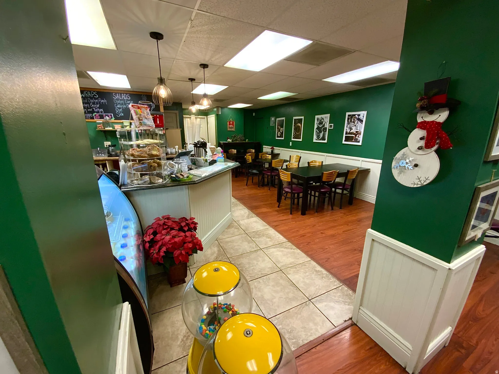 Kitchen featuring wainscoting, a drop ceiling, decorative light fixtures, white cabinets, and dark countertops