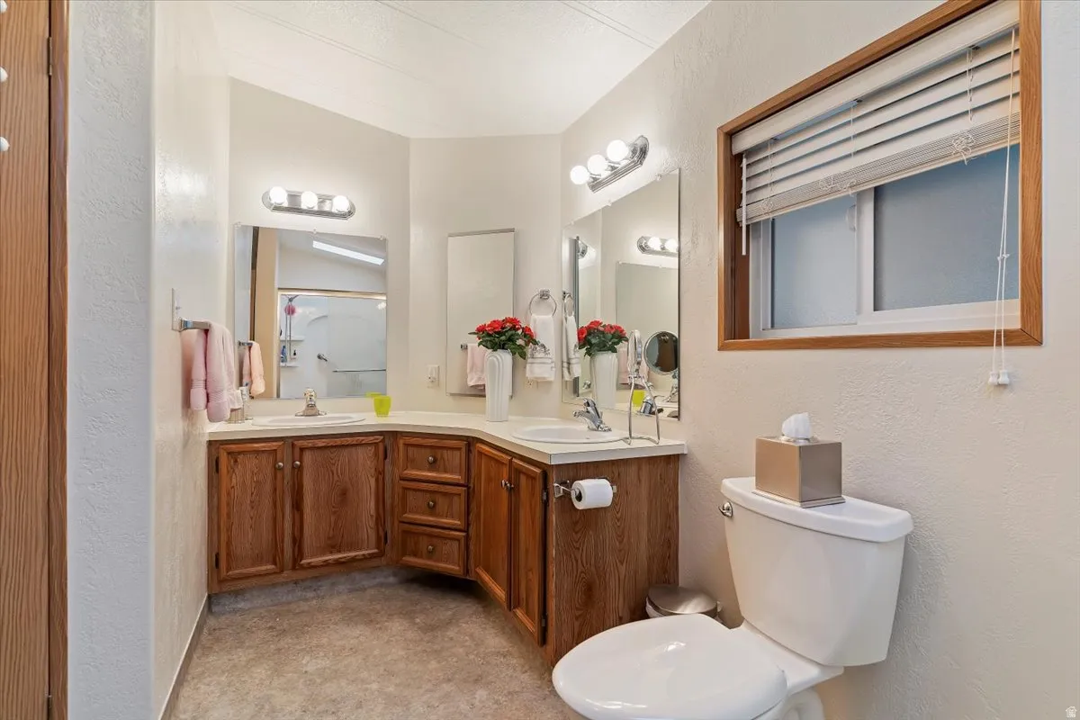 Full bath with a textured wall, double vanity, and a shower with door