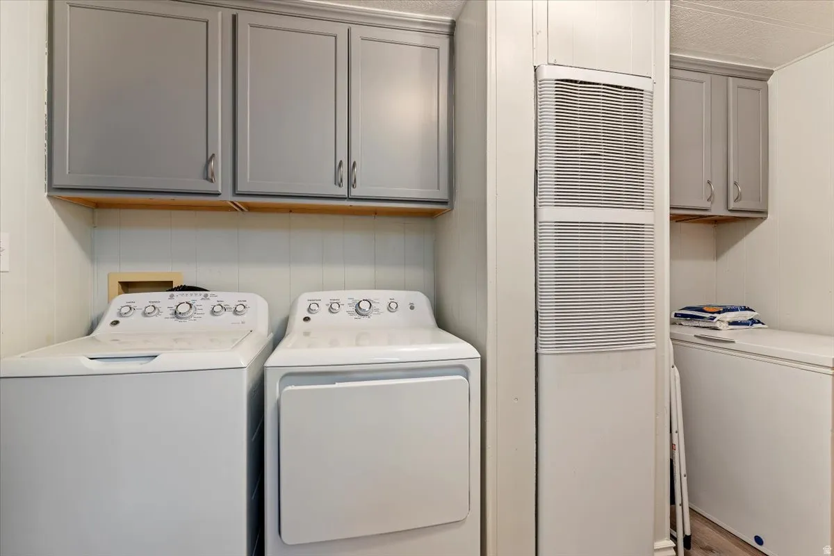 Laundry area featuring a heating unit, cabinet space, independent washer and dryer, and a decorative wall