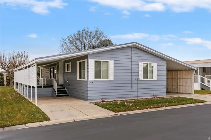 View of front facade with covered porch, concrete driveway, and a front lawn