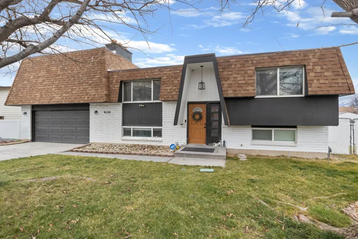 View of front of house featuring roof with shingles, mansard roof, driveway, brick siding, and a garage