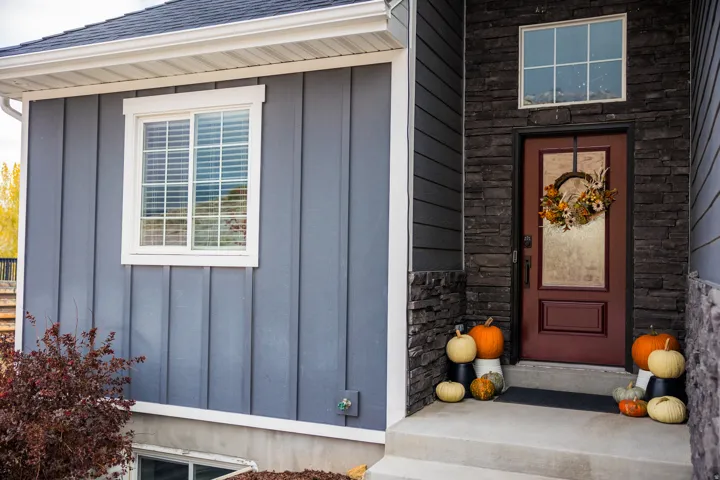 View of exterior entry with board and batten siding and roof with shingles