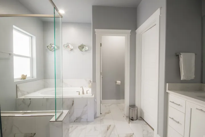 Bathroom featuring a garden tub, light marble finish floors, and vanity