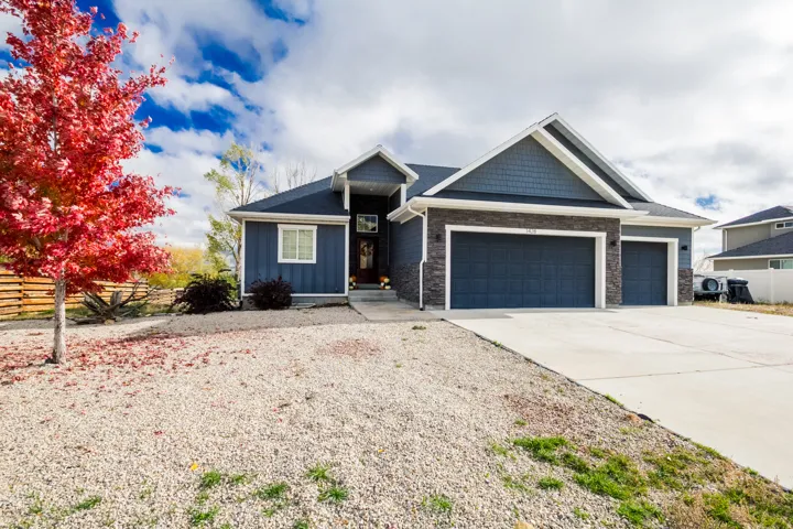 View of front of home featuring driveway, an attached garage, board and batten siding, and stone siding