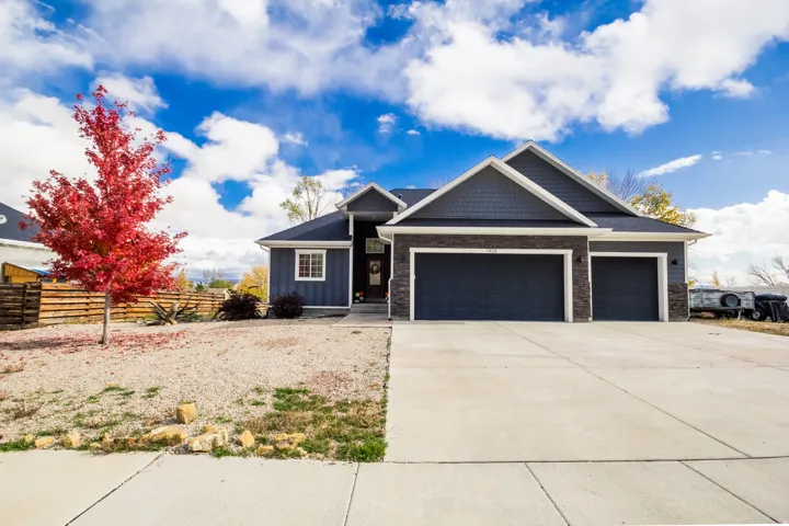 View of front of home featuring board and batten siding, stone siding, a garage, and driveway