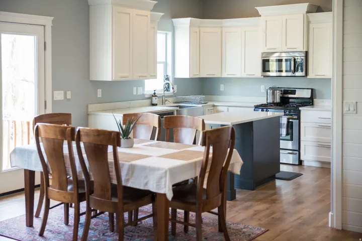 Kitchen with appliances with stainless steel finishes, white cabinets, dark wood-style flooring, a center island, and light stone countertops