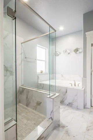 Full bath featuring a garden tub, a marble finish shower, and marble finish floors