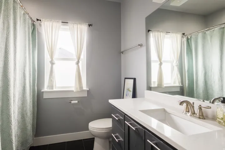 Full bath with curtained shower, vanity, dark tile patterned floors, and plenty of natural light