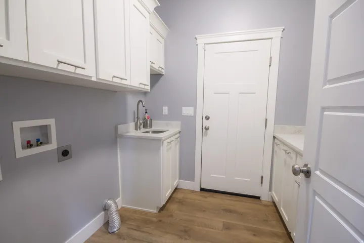 Washroom with electric dryer hookup, dark wood-type flooring, cabinet space, and washer hookup