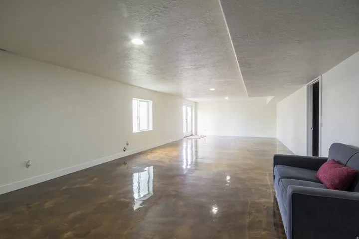 Living area with a textured ceiling, recessed lighting, and finished concrete flooring