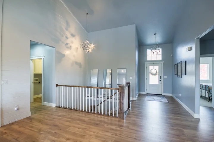 Foyer entrance featuring high vaulted ceiling, a chandelier, and wood finished floors