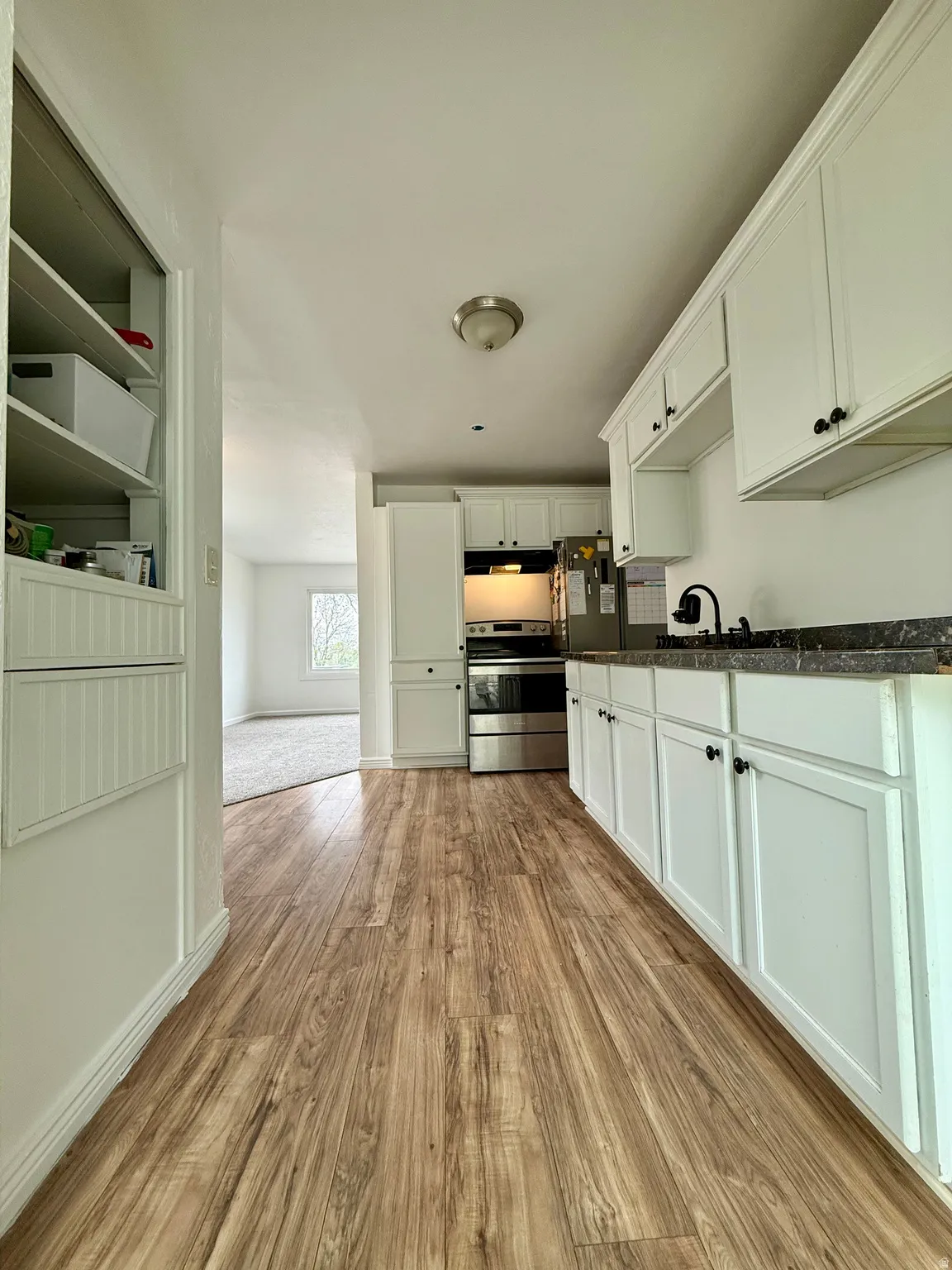 Kitchen with light wood-type flooring, white cabinetry, and stainless steel electric range oven