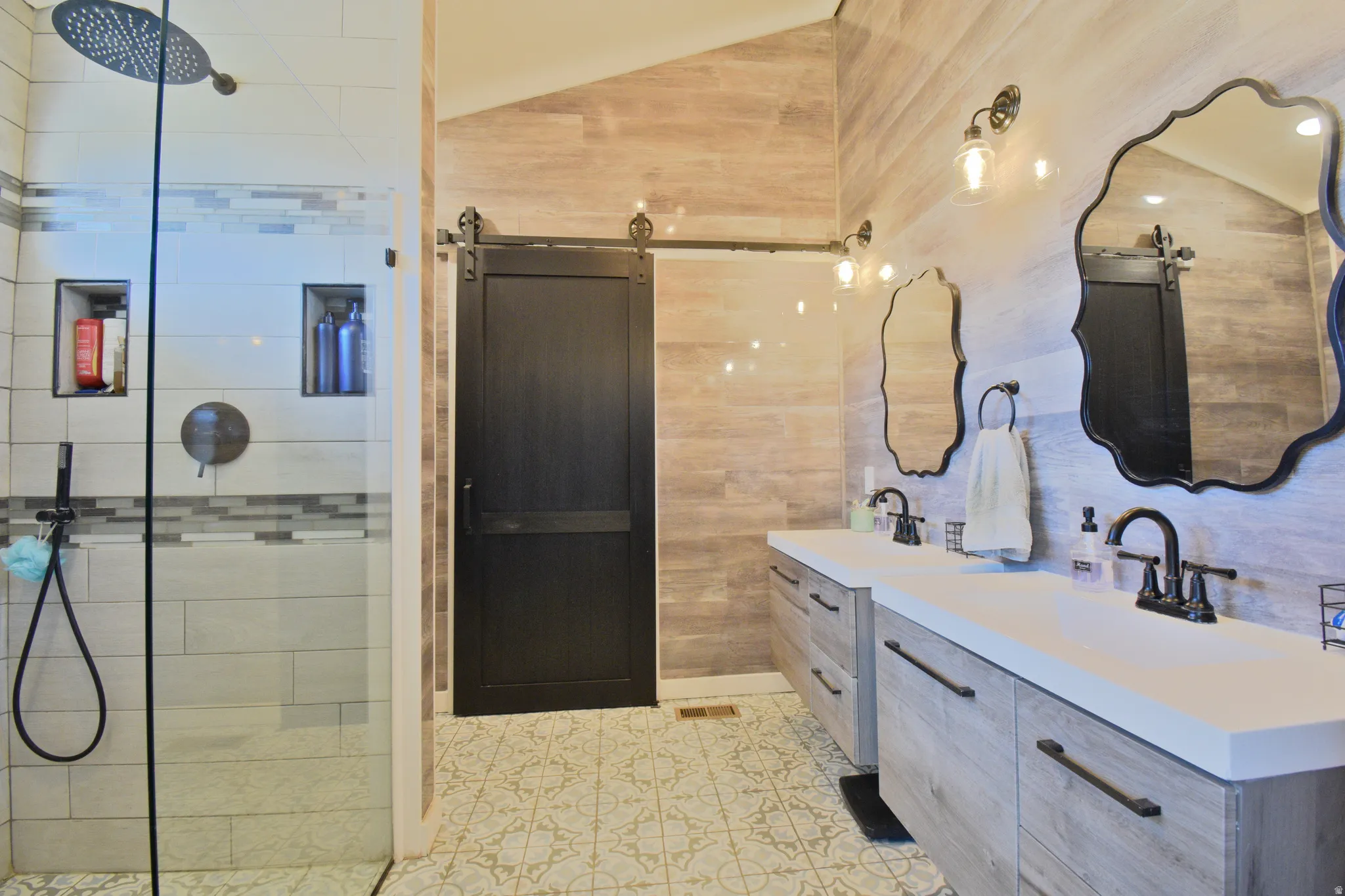 Bathroom with vaulted ceiling, two vanities, and a tile shower